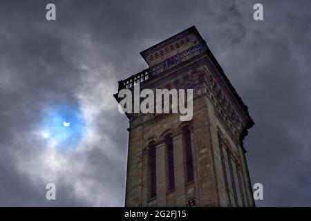 Parziale eclissi solare come visto a Glasgow Scozia il 10/06/2021 Trinity Tower in primo piano con cielo drammatico e patch di blu dal sole. Foto Stock