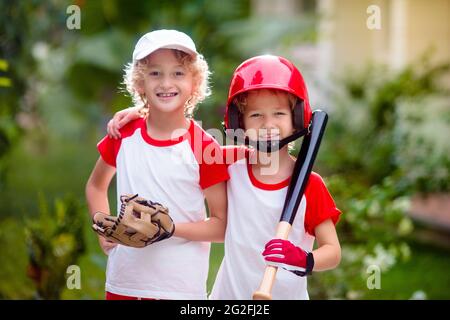 I bambini giocano a baseball. Bambino con pipistrello e palla. Attività all'aperto per bambini sani. Divertente gioco di palla di squadra per ragazzo e ragazza. Giovane atleta sul campo da baseball. Foto Stock