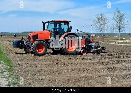 Podersdorf, Austria - 04 maggio 2021: Aiuti sconosciuti su un trattore che piantano vite meccanicamente Foto Stock