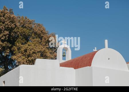 Vista ad angolo basso della chiesa con cupola rossa su una collina a Mykonos, in Grecia, contro il cielo blu. Foto Stock