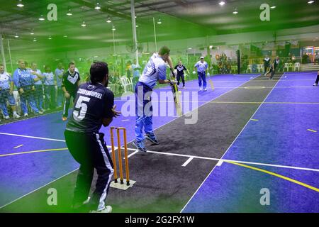 Batsman si alza per giocare un tiro fuori dal piede posteriore in una partita di Cricket indoor Foto Stock