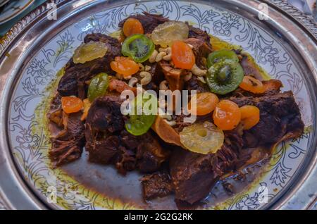 Un piatto di carne marocchina decorato con albicocche, ananas e kiwi. Cibo marocchino per matrimoni Foto Stock