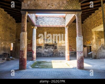 Atrio in stile tetraidro con quattro colonne ioniche intorno ad un impianto centrale. L'atrio è decorato nel quarto stile con pannelli rossi, neri e gialli Foto Stock