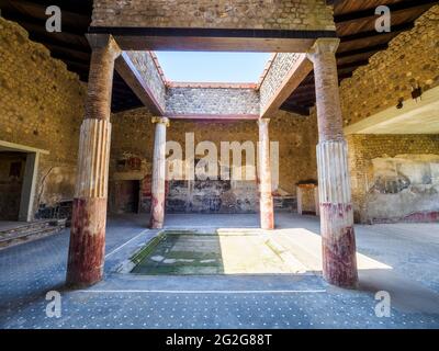 Atrio in stile tetraidro con quattro colonne ioniche intorno ad un impianto centrale. L'atrio è decorato nel quarto stile con pannelli rossi, neri e gialli Foto Stock