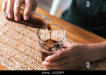 Versare il caffè freddo ghiacciato dalla bottiglia nel bicchiere Foto Stock