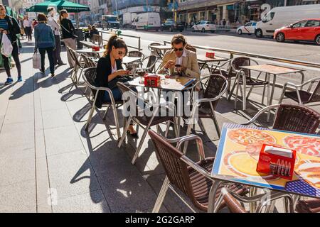 Coppia seduta su una terrazza che consulta il telefono. Gran Vía Avenue, Madrid, Comunidad de Madrid, Spagna, Europa Foto Stock