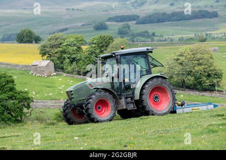 Pascoli con un'altura, con un trattore Hurlimann e un topper Fleming, che lo liberano dai vampate. North Yorkshire, Regno Unito. Foto Stock