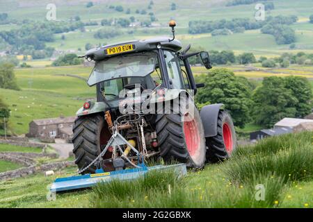 Pascoli con un'altura, con un trattore Hurlimann e un topper Fleming, che lo liberano dai vampate. North Yorkshire, Regno Unito. Foto Stock