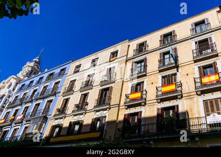 Vista parziale con balconi adornati da bandiere di Spagna. Calle Mayor, strada principale, è una strada centrale di Madrid, Spagna. Situato nel Centro Dis Foto Stock