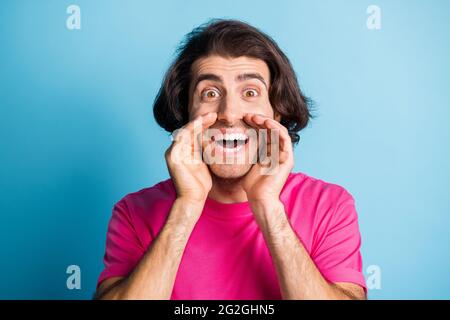 Foto di uomo sorpreso scream annunci promo indossare t-shirt rosa isolato su sfondo di colore blu Foto Stock