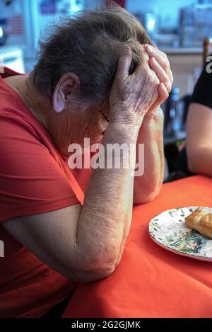 Una donna latina di 84 anni, pregando prima del suo pasto. Foto Stock