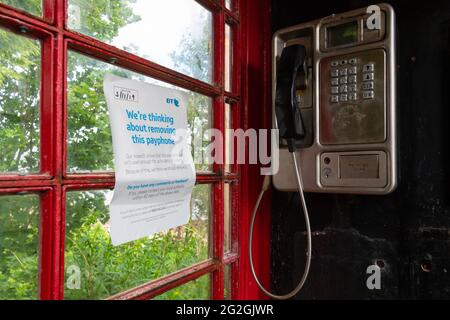 "Stiamo pensando di rimuovere questo telefono a pagamento" all'interno della tradizionale scatola telefonica rossa bt, Strachur, Argyll e Bute, Scozia, Regno Unito Foto Stock