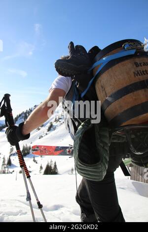 Uomo con barile di birra Mittenwald sulla schiena, sci da turismo, attrezzature di fronte alla cima del Rotwandkopf (1,858 m) Rotwand (1,884 m) nelle montagne Mangfall, Spitzingsee, alta Baviera, Baviera, Germania, Foto Stock