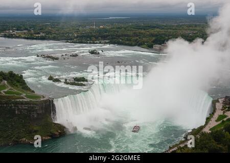 Vista panoramica delle Cascate del Niagara Tour in barca a vela nella cascata delle Cascate Horseshoe con nebbia d'acqua che scende verso il cielo, Ontario, Canada Foto Stock