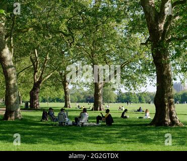 Londra, Greater London, England - 27 maggio 2021: Gli amici si siedono e chiacchierano in una soleggiata giornata di primavera ad Hyde Park. Foto Stock