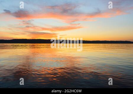 Il sole tramonta su Puget Sound nello stato occidentale di Washington creando uno sfondo di forme rosa e arancione nel cielo serale Foto Stock