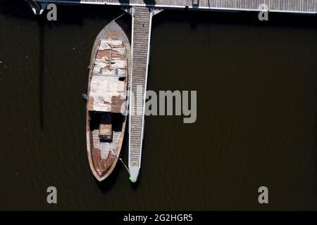 Una vecchia barca poggia su un molo di legno. Foto Stock