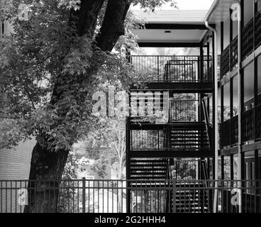 Appartamento edificio scale esterne e albero con recinzione in bianco e nero Foto Stock
