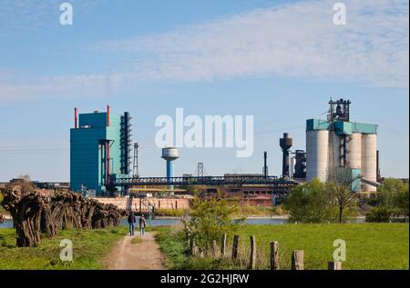 Duisburg, Renania Settentrionale-Vestfalia, Germania - paesaggio industriale nella zona della Ruhr, passeggini a piedi sul Reno di fronte allo sfondo industriale di HKM Huettenwerke Krupp Mannesmann. Foto Stock