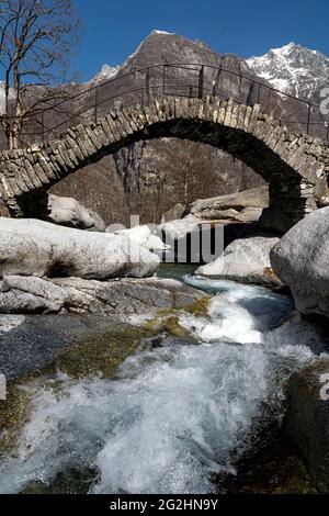 In una piccola valle laterale della Valle Maggia, questo antico ponte in pietra si estende su un piccolo ruscello montano. Foto Stock