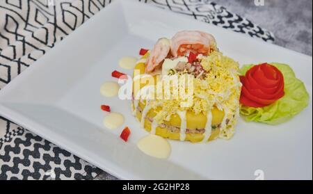 Cibo peruviano: Causa rellena de atun. Tonno causa rellena. Piatto tradizionale peruviano di patate gialle, tonno, avocado su piatto bianco. Messa a fuoco selettiva Foto Stock