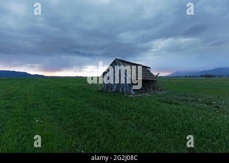 Capanna su un prato ai piedi delle Alpi, tramonto Foto Stock