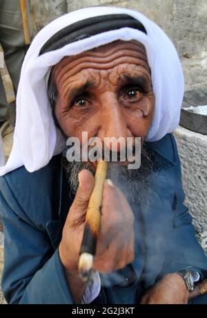 Un uomo palestinese anziano che fuma la sigaretta nel quartiere musulmano della città vecchia di Gerusalemme. Foto Stock