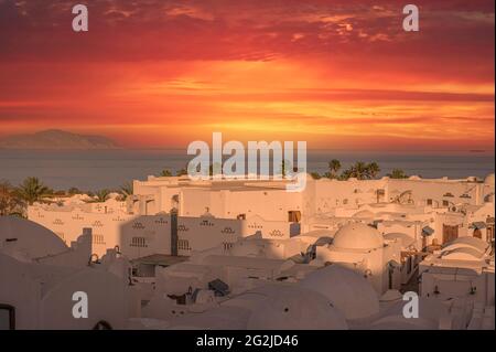 favolosa e misteriosa città araba bianca sotto il suggestivo tramonto del cielo rosso. Vista aerea. Tetti e cupole di un'antica città araba al tramonto Foto Stock