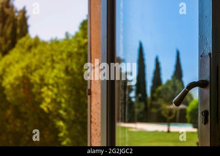Paesaggio del parco, specchiato nella porta di vetro di una finca a Maiorca, vista dettagliata della maniglia della porta Foto Stock
