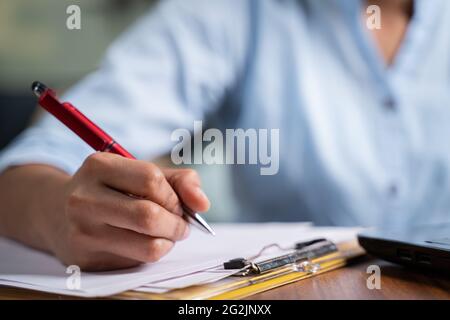 Mettere a fuoco sulla mano, chiudere le mani irriconoscibili di giovane donna di affari che scrive le note alla scrivania di lavoro - concetto di dipendente o studente in linea Foto Stock