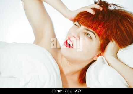 la ragazza si sveglia e sbadiglia. la ragazza con i capelli rossi Foto Stock
