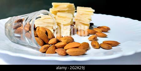 Badam Katli è un dolce indiano a forma di diamante con mandorle fatte usando mandorle, zucchero e mava, servito in un piatto isolato su sfondo bianco. Selettivo Foto Stock