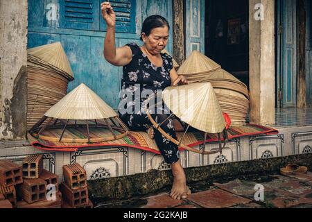 Vietnamita vecchia donna artigiana che fa il cappello tradizionale vietnam nella vecchia casa tradizionale in AP Thoi Phuoc villaggio, Hochiminh città, Vietnam, trad Foto Stock