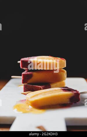 Le papicole fatte in casa sono di frutta fresca di mango, ribes nero e latte di cocco. Sano dessert estivo vegano. Foto Stock