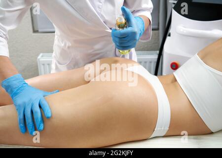 Cosmetologa idratare la pelle di natiche di una donna con olio. Concetto di sollevamento e serraggio Foto Stock