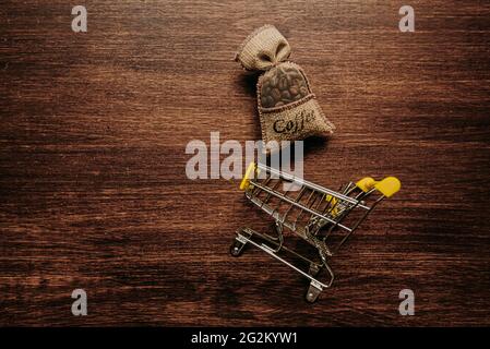 chicchi di caffè in una borsa carrello carrello cestino sfondo di legno scuro. Foto Stock