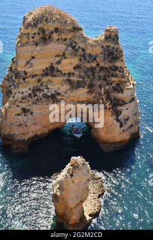 Navigazione in barca attraverso una grotta naturale di roccia a Ponta da Piedade vicino Lagos, Algarve, Portogallo Foto Stock