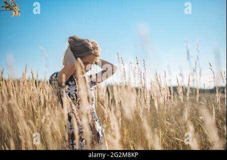 Bellezza Romantica ragazza all'aperto. Bella ragazza modello teenage vestito in abito casual sul campo in luce solare. Glow Sun, sole Foto Stock