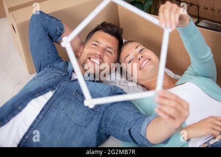 felice coppia che fa la forma della casa con il righello pieghevole Foto Stock