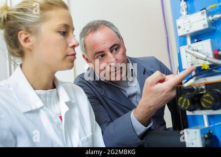 ingegnere che istruisce l'apprendista femminile sull'uso della macchina cnc Foto Stock