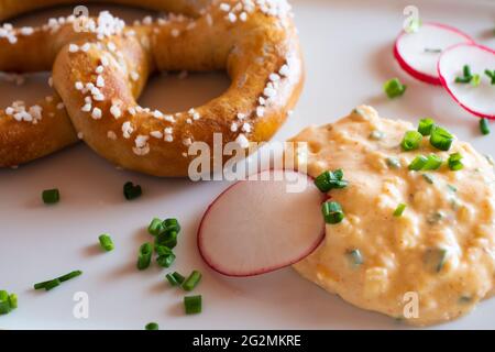 Obatzda, un formaggio bavarese diffuso anche chiamato Obatzter o Obazda con un Pretzel chiamato Brezel o Laugenbrezel Foto Stock