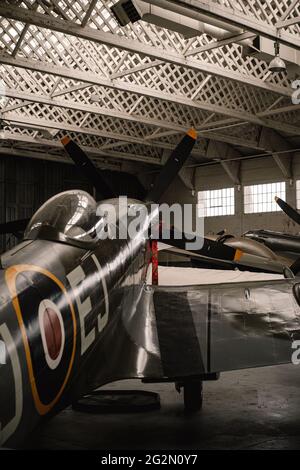 Duxford Inghilterra Maggio 2021 scatto verticale del lato posteriore di uno spitfire all'interno di un hangar, colori scuri retrò seppia Foto Stock