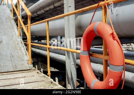 Life boe attaccate e sospese sulla recinzione del ponte sul mare, boe di sicurezza gialle Foto Stock