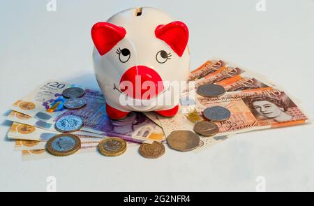 Piggy bank con banconote e contanti in sterlina britannica Foto Stock