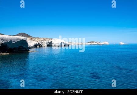 Isola di Milos, Sarakiniko. CICLADI Grecia. Paesaggio lunare, formazioni rocciose di colore bianco, scogliere e grotte, mare ondulato blu e cielo trasparente. Estate Foto Stock