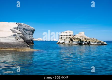 Isola di Milos, Sarakiniko. CICLADI Grecia. Paesaggio lunare. Formazioni rocciose di colore bianco, scogliere e caverne, mare ondulato blu e cielo chiaro sfondo. Foto Stock