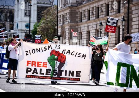 Londra, Regno Unito. 12 giugno 2021. I manifestanti marciano lungo Whitehall, mentre tenevano un grande striscione che diceva che il sionismo è il razzismo, la Palestina libera durante una manifestazione che chiede giustizia per la Palestina. Dal maggio 2021 Israele ha lanciato 11 giorni di bombardamenti aerei a Gaza, uccidendo 248 persone, di cui 66 bambini e lasciando più di 1,900 feriti. Inoltre, i bombardamenti di Hamas in Israele nello stesso periodo hanno ucciso 12 civili, tra cui due bambini. Molti gruppi pro-palestinesi hanno protestato nelle città di tutto il mondo. Credit: SOPA Images Limited/Alamy Live News Foto Stock