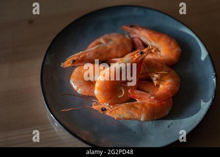 Gamberi cotti a piedi bianchi del pacifico su un piatto blu. Foto Stock