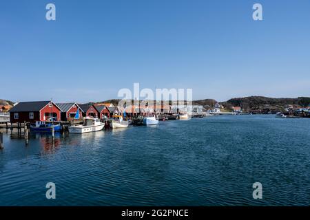 17 aprile 2021 - Hamburgsund, Svezia: Un pittoresco villaggio di pescatori sulla costa occidentale svedese. Tradizionali capanne di mare rosso e un cielo blu sullo sfondo Foto Stock