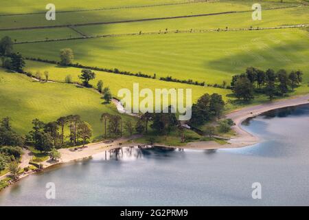 Vivaci campi verdi sulla riva del lago Buttermere in un pomeriggio estivo soleggiato. Lake District, Regno Unito. Foto Stock